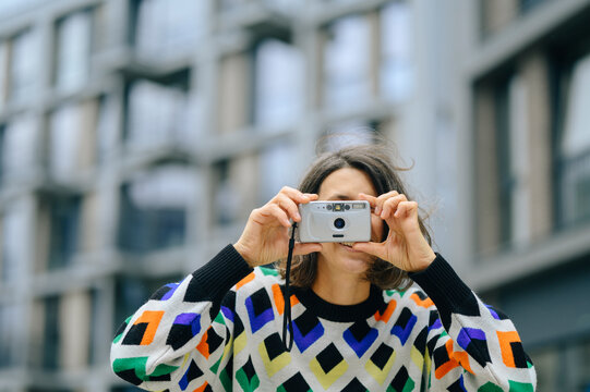 Mature woman photographs with a retro camera outdoors in the city