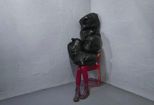 Woman hides herself under heap of garbage bags
