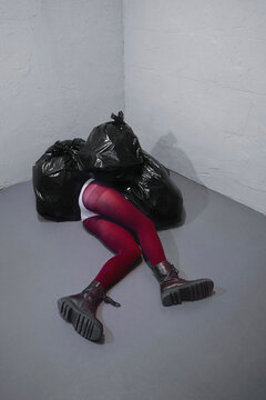 A fallen woman hides her body under black garbage bags