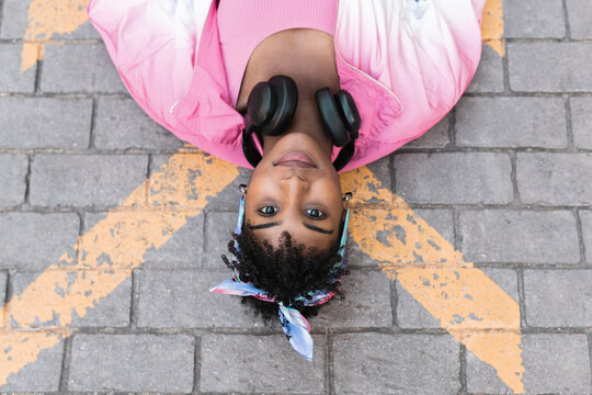 Young woman wearing headphones while lying on road
