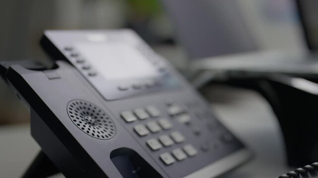 Close-up of a business woman's hand answering a telephone call at an office desk corporate workspace setting