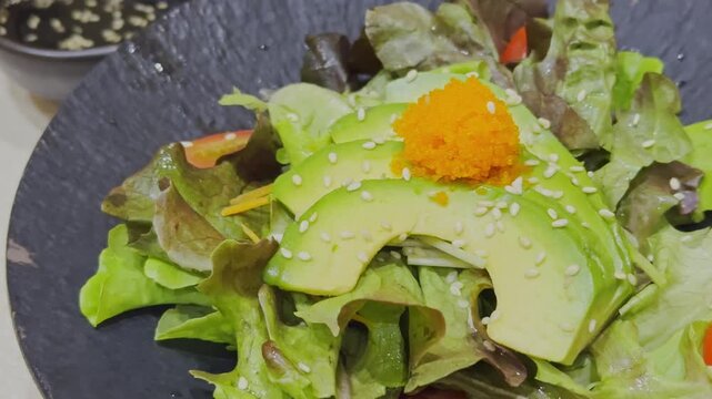 Close-up video of a fresh Japanese-style avocado salad beautifully arranged with mixed vegetables and traditional Japanese dressing. Healthy and colorful salad presentation showcasing authentic Japane