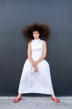 Confident woman wears white dress against black background