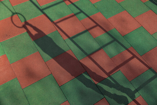 Shadow of a boy hanging on playground ring and ladder outdoors