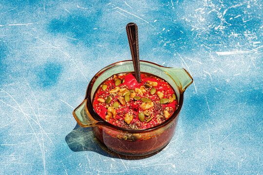 Healthy vegan beetroot soup with seeds and nuts on blue background