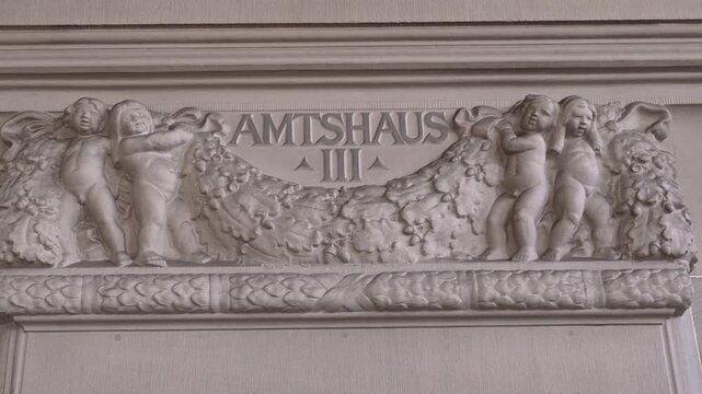 Ornate Amtshaus III interior relief shows four putti holding garlands above a doorway in the Zurich district court building.
