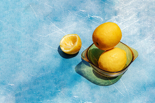 Fresh lemon in a glass bowl on a blue textured background
