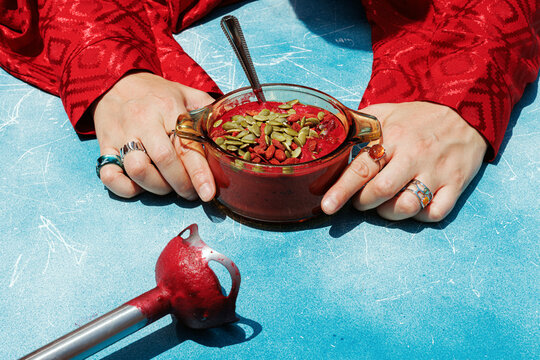 Hands holding a bowl of healthy vegan beetroot soup with seeds