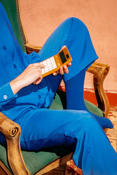 Hands in blue outfit using a retro calculator for budgeting