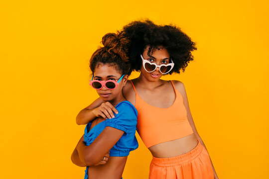 Fashionable young friends wearing sunglasses against yellow background