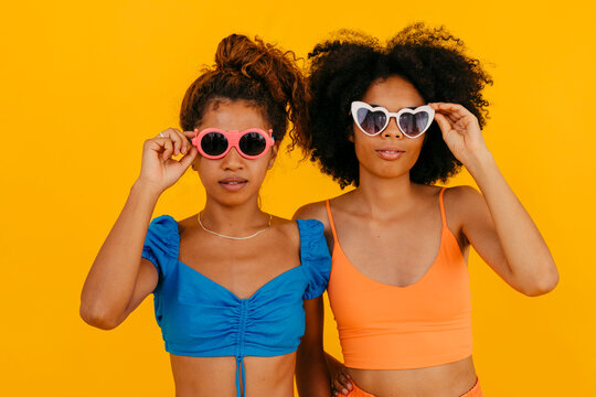 Fashionable friends wearing sunglasses against yellow background