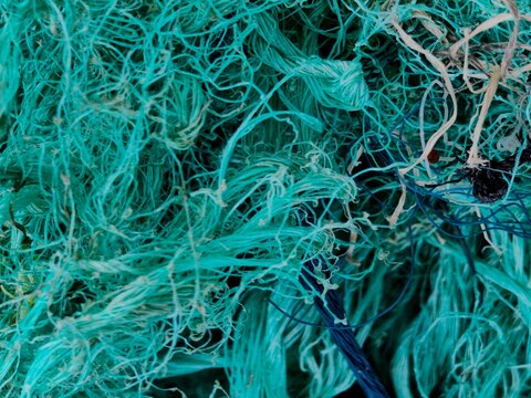 Full frame texture of tangled green plastic fishing net mesh. Marine debris and microplastic source background.