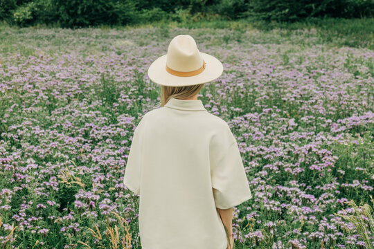 Woman in white hat relaxes in a summer phacelia meadow