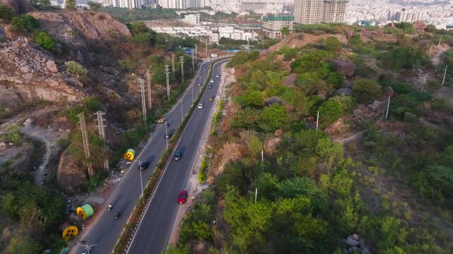 Nanakramguda OOR to lanco hills road with vehicles and surrounding rocky terrain at Makthakousarali, Khajaguda, hyderabad, telangana, india. day time, push in shot, drone shot, 4k.