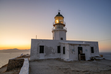 Armenistis Lighthouse on Mykonos at dusk, side view with lit lantern and sunset afterglow over the Aegean Sea, Cyclades, Greece  © Michal Plevko