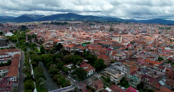 cinematic aerial drone orbit around la merced church in cuenca ecuador revealing the gorgeous tomebamba river and the sprawling historic cityscape in the beautiful background on a warm clear sunny day