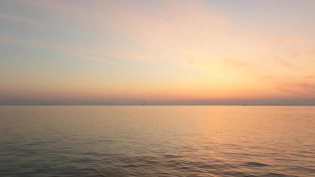 Cinematic video of a peaceful morning sunrise over minimal calm glassy ocean with a clear horizon