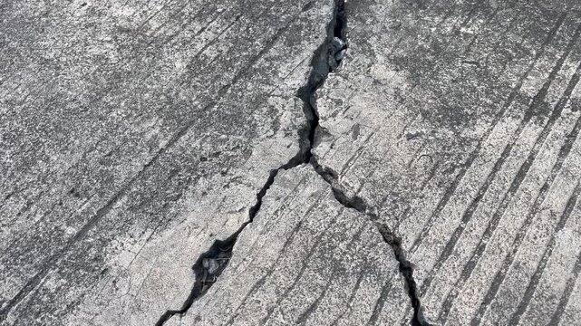Deep diagonal crack on rough textured concrete surface
