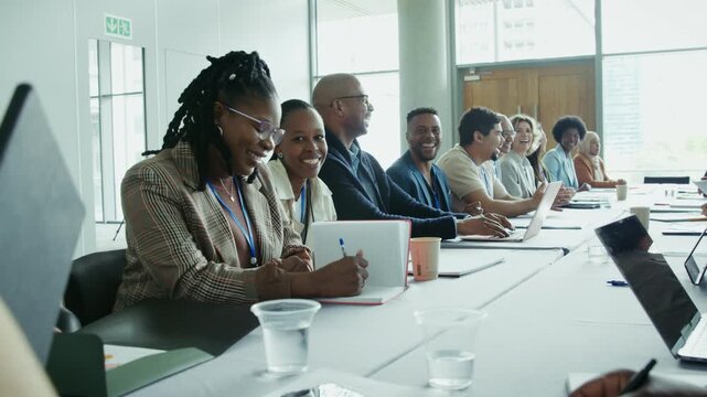 Diverse group of professionals collaborating and interacting cheerfully at a modern business meeting or conference. Participants are smiling, laughing, and actively engaged in the positive event.
