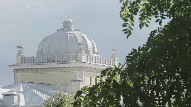 Historic white synagogue dome framed by green tree leaves