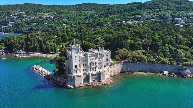 Trieste, Italy - 4K Flying around of the beautiful Miramare Castle (Castello di Miramare) by the Gulf of Trieste on a sunny summer day with blue sky and turqoise sea water