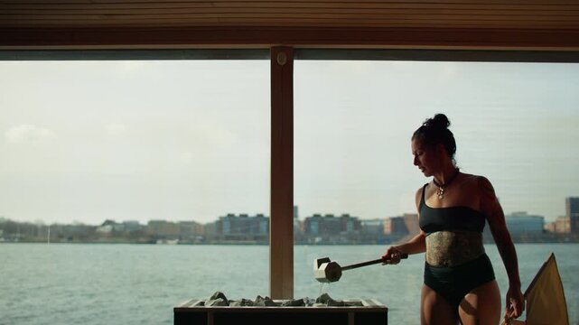 Sauna aufguss ritual with woman fanning steam in premium spa interior