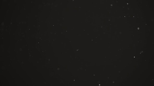 Floating dust particles over dark background with shallow focus