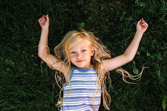 A little girl enjoys the green grass outdoors