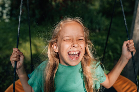 Laughing girl having fun on a swing outdoors on a sunny summer day