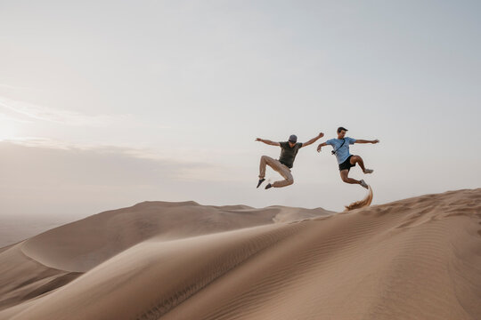 Namibia, Namib, two friends jumping in the air on desert dune