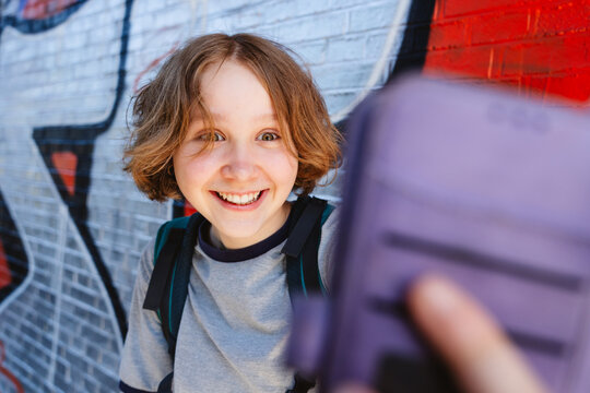 Smiling girl looks at a smartphone outdoors