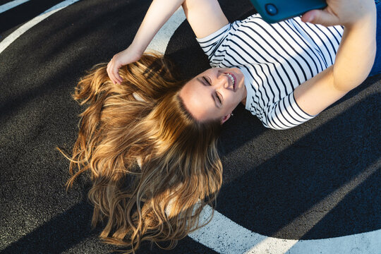 Smiling woman takes a selfie with her smartphone on the asphalt