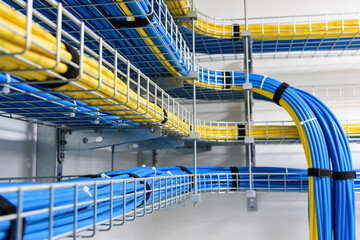 Organized network cables in blue and yellow neatly routed through wire mesh trays © Snide12