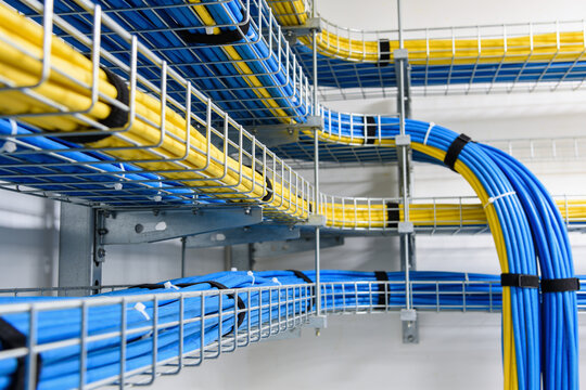 Organized network cables in blue and yellow neatly routed through wire mesh trays