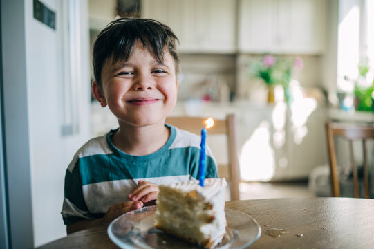 A smiling boy celebrates his birthday with a cake indoors