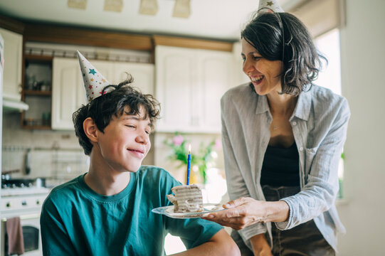 Mother holds birthday cake for her son in the kitchen