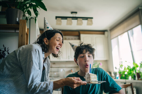 Smiling mother and son celebrate a birthday with cake in the kitchen