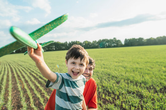 Father and son playing with a toy airplane in the park
