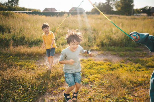 A happy boy jumps rope in the sunny yard during summer holidays
