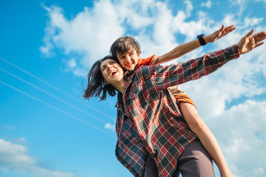 Mother gives her son a piggyback ride in a summer field