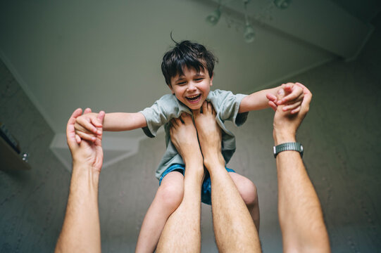 Father lifts his laughing son up in the air at home