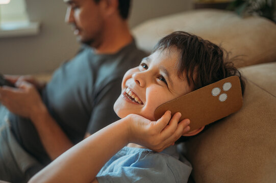 Smiling boy plays with a cardboard smartphone at home