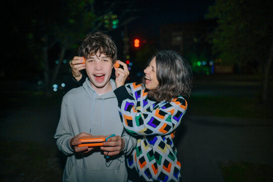 Mother and son laughing while listening to music outdoors at night