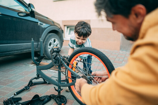 Father and son repair a bicycle together outdoors