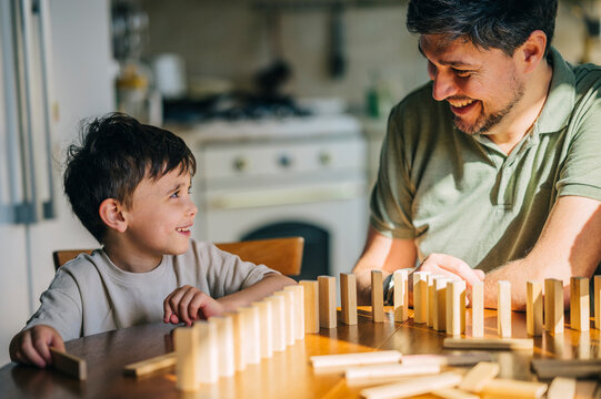 Father and son playing with wooden domino blocks at home