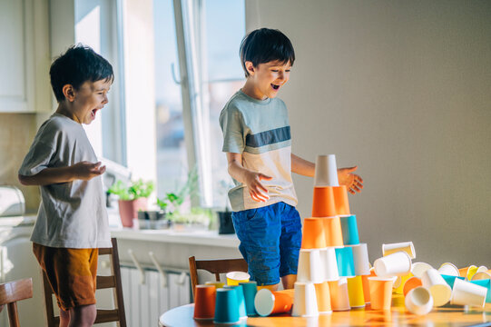 Excited children building a colorful paper cup tower at home