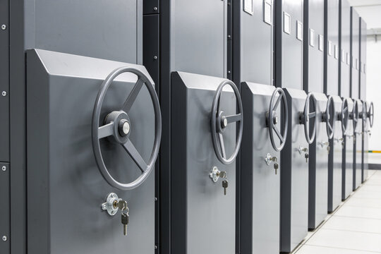 Row of secure vault doors with large wheels and keys, emphasizing safety and access