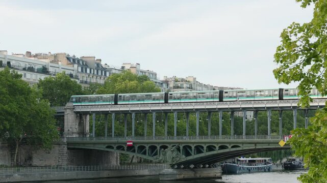 Paris Metro Train Traveling Across the Multi-Level Pont de Bir-Hakeim Over the Seine River Framed by Green Foliage