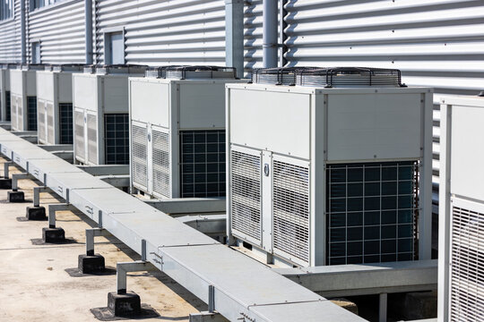 Row of industrial air conditioning units on a rooftop with corrugated metal siding