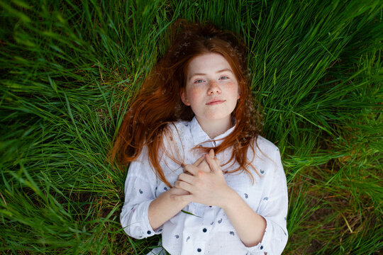 A woman in a white blouse enjoys the green grass during summer